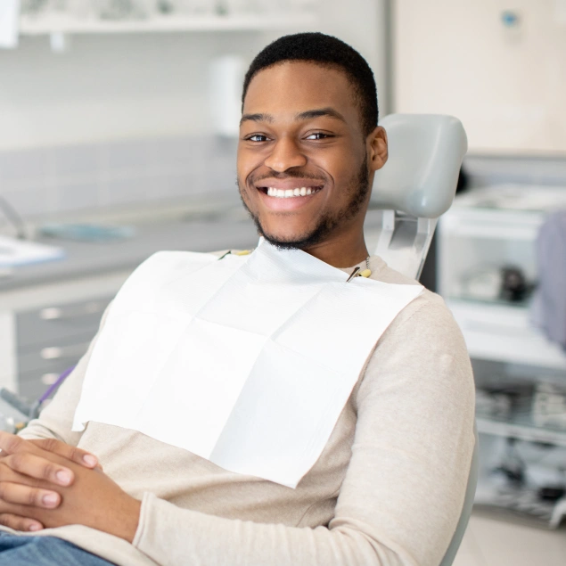 Smiling man in dental bib at Lakeside Family & Cosmetic Dentistry office with equipment in background.