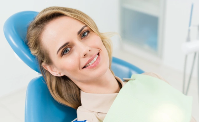 Woman smiling in dental chair at modern dental office during examination or consultation.