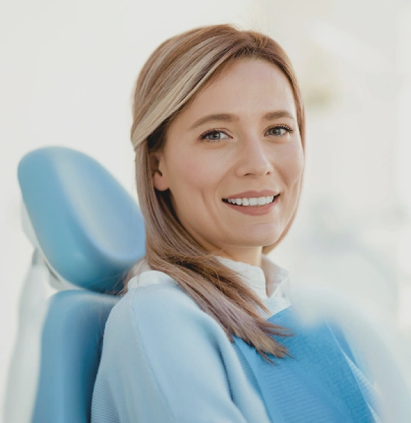 Smiling woman in dental chair at modern dentistry office, wearing blue bib.