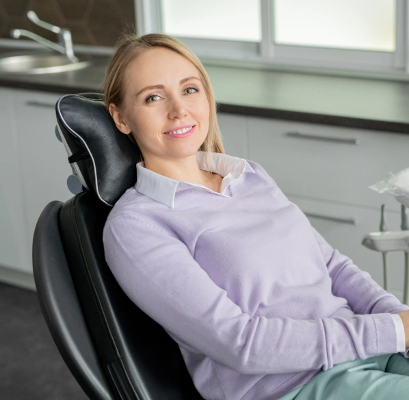 Woman in lavender shirt sitting in dental chair at modern dentistry office