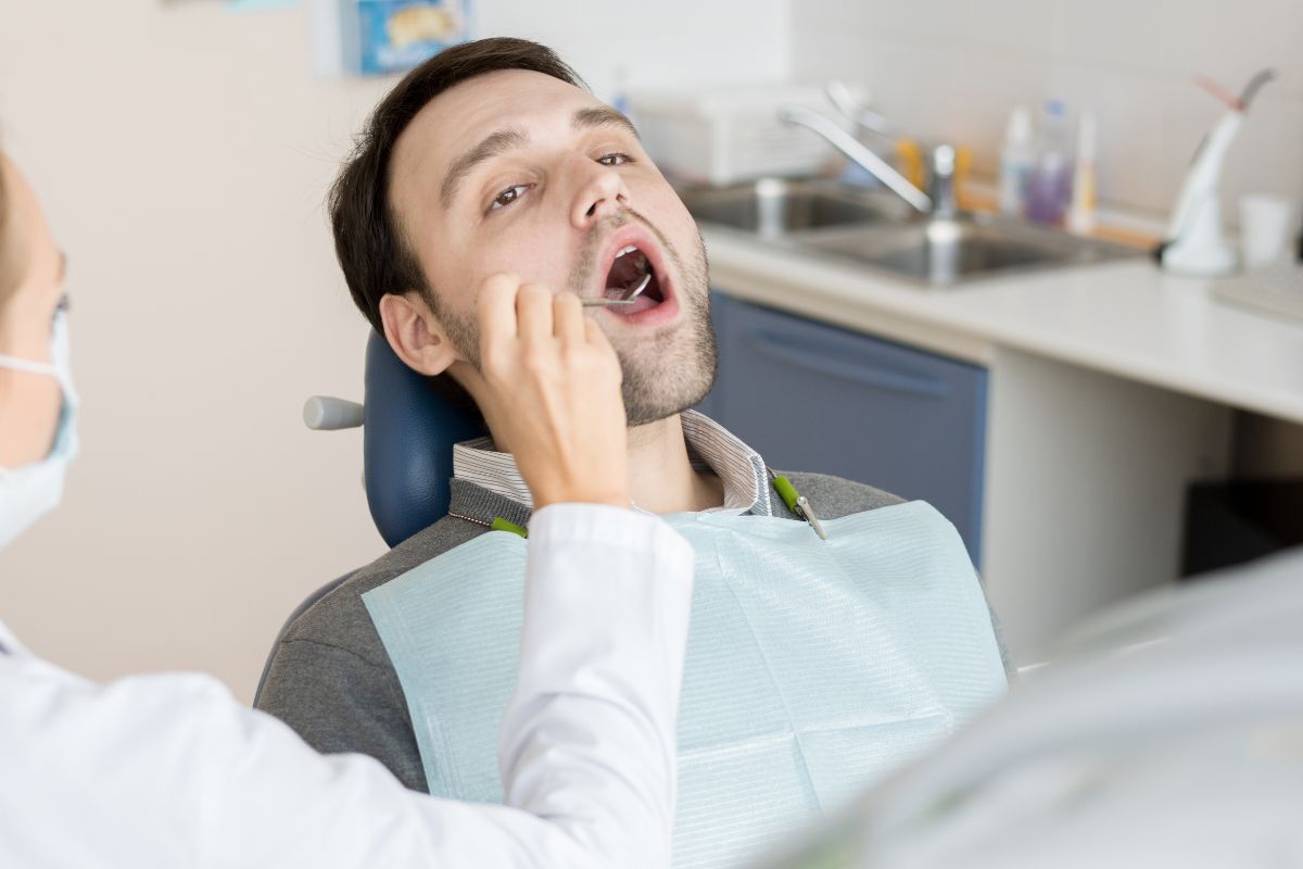 Male patient with mouth open during dental examination in treatment chair.
