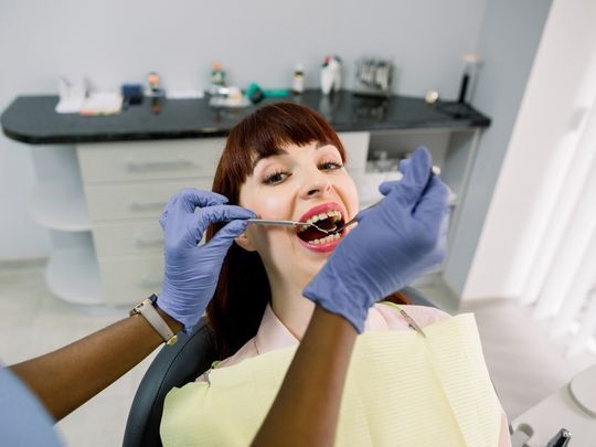 Dentist examining patient's teeth during oral examination in dental office.