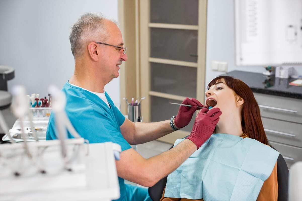 Dentist examining patient's teeth during oral examination in modern dental office.